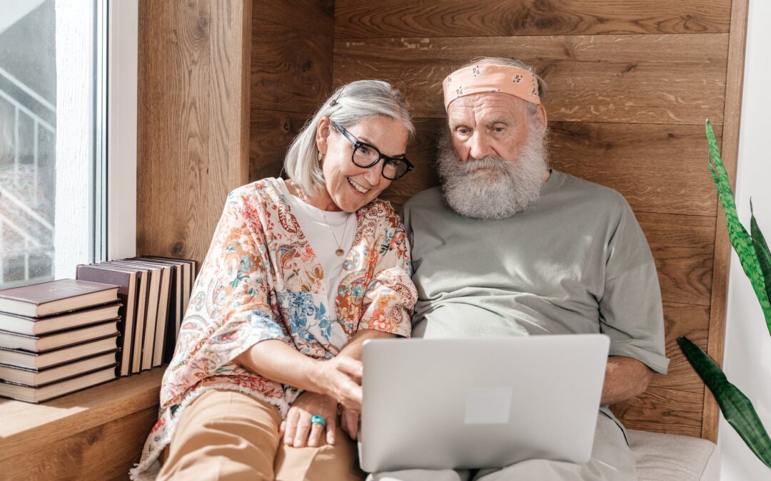 senior couple using laptop on a bed and wooden wall in background