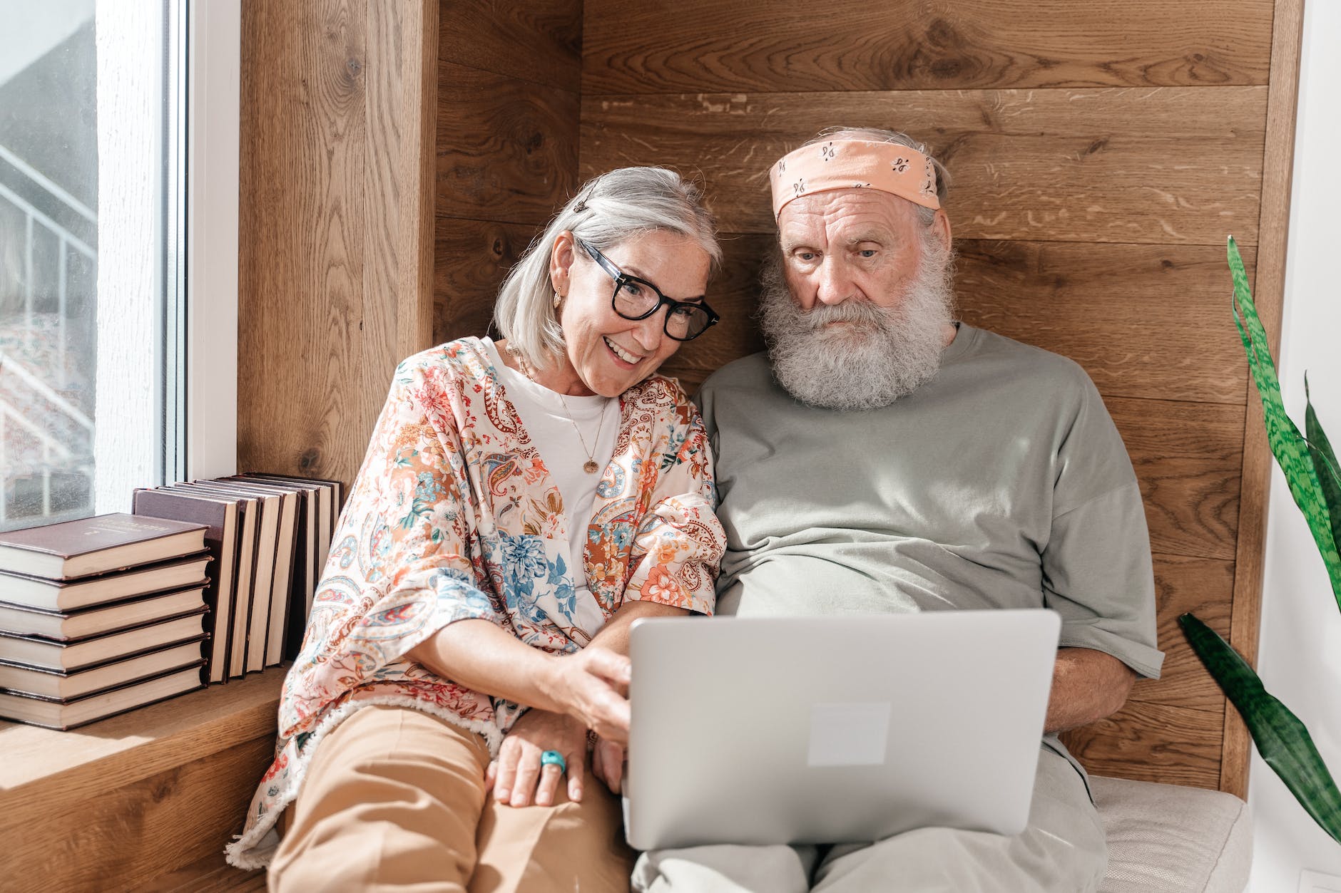 senior couple using laptop on a bed and wooden wall in background